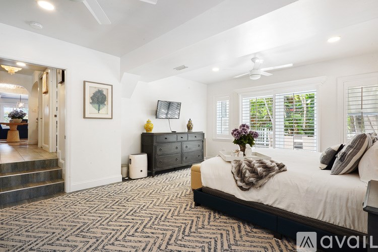 A bedroom with a large bed, a dresser, and a painting on the wall.