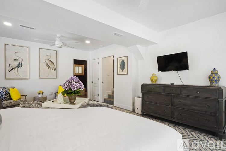 A bedroom with a bed, dresser, and television.