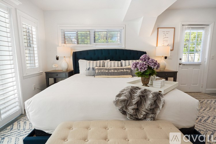A bedroom with a large bed and a vase of flowers on the bed.