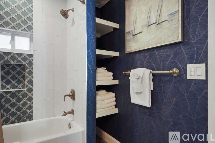 A bathroom with a white bathtub and a blue wallpaper.