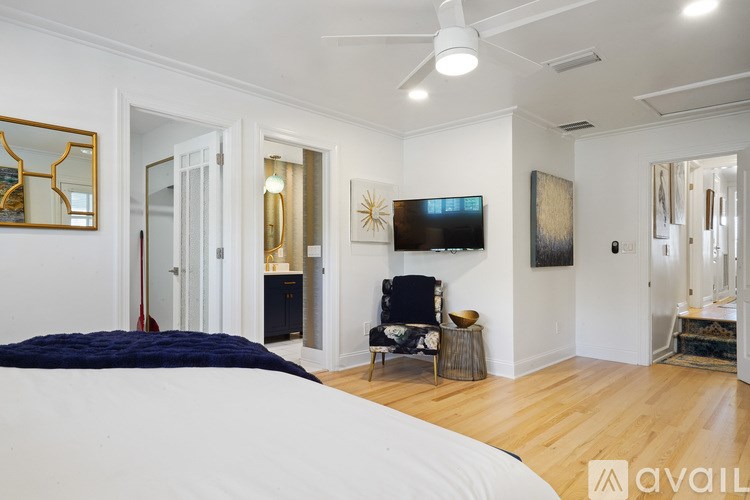 A bedroom with a bed, chair, and mirror.