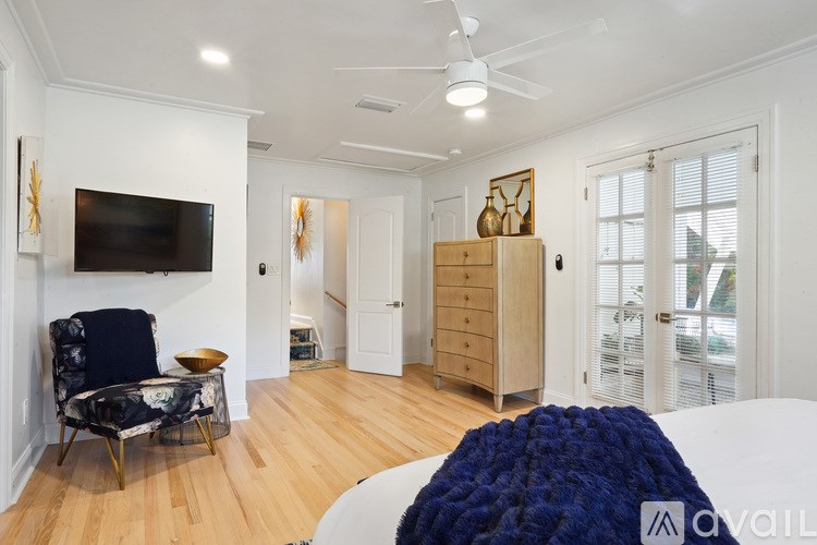 A living room with a black chair and a television on the wall.