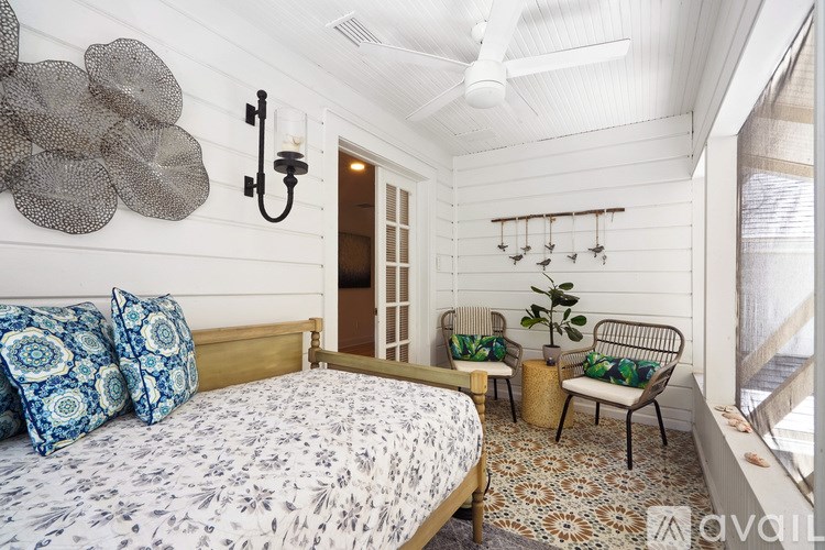 A bedroom with a bed, two chairs, and a wall decoration.