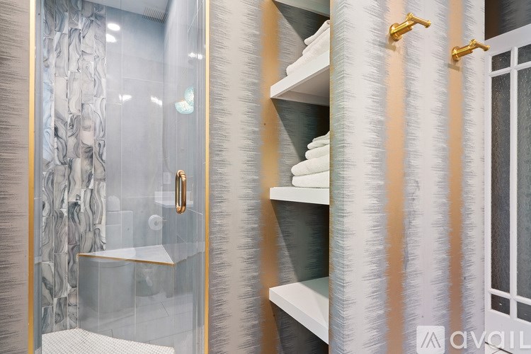 A bathroom with a glass shower door and a white shelf.