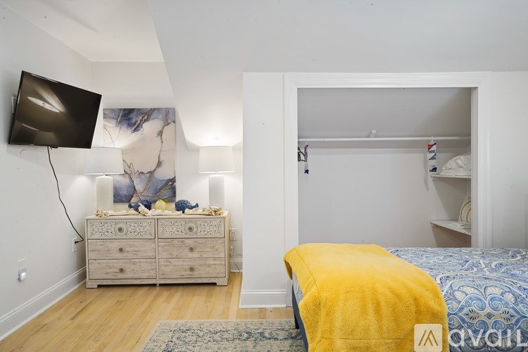 A bedroom with a bed, a dresser, and a television.