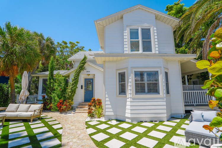 A white house with a blue door and a white fence.