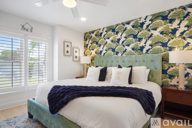 A bedroom with a bed, a ceiling fan, and a wallpapered wall.