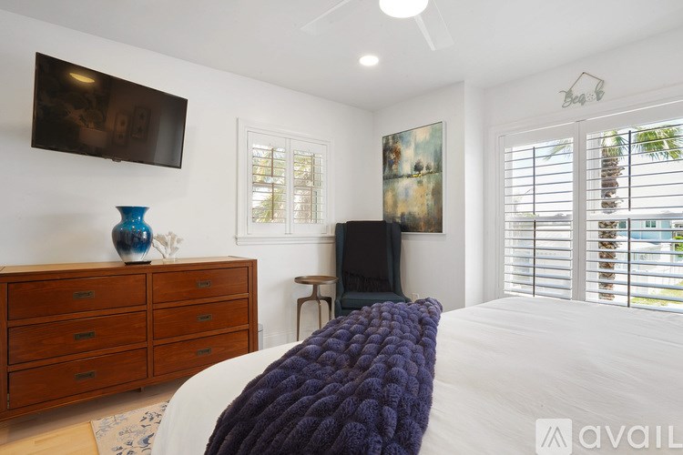 A bedroom with a bed, a dresser, a TV, and a painting on the wall.