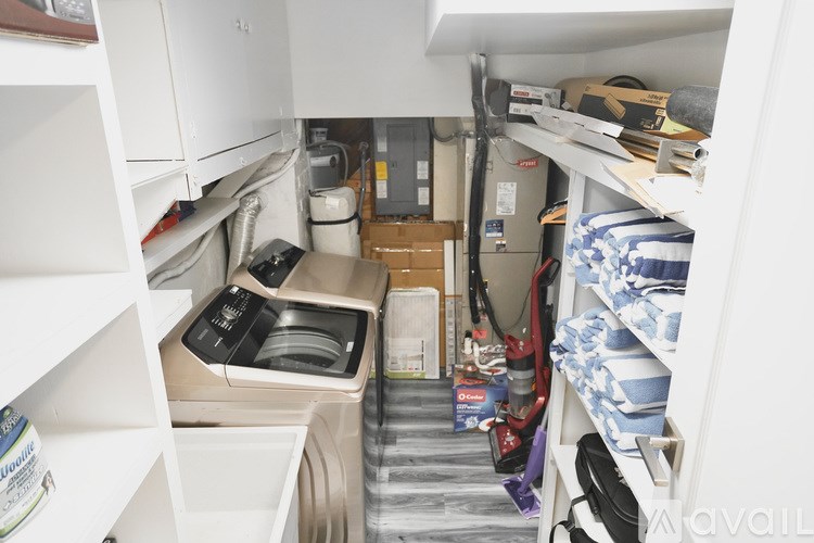 A small, cluttered kitchen with a washing machine and a coffee maker.