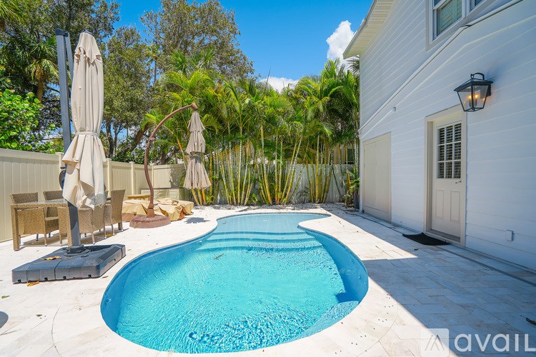 A pool surrounded by a white fence and trees.