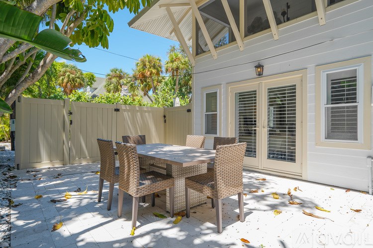A patio with a table and chairs is covered in leaves.
