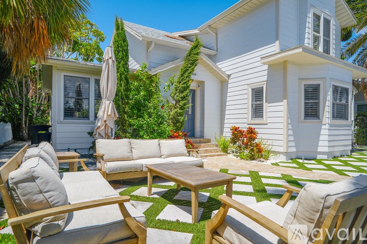 A white house with a patio and wooden furniture.