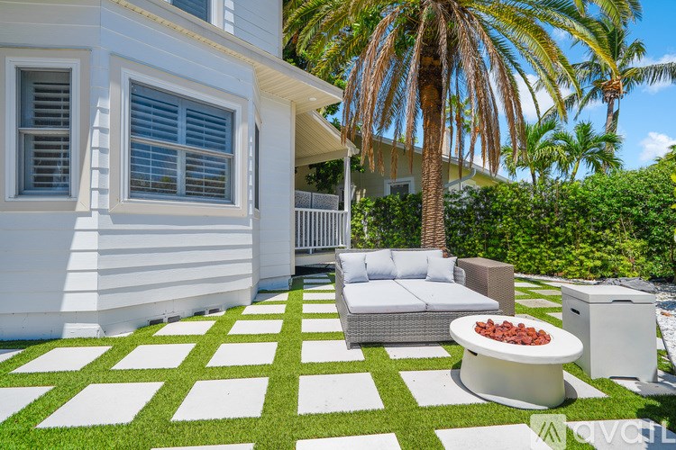 A white house with a patio and a palm tree.
