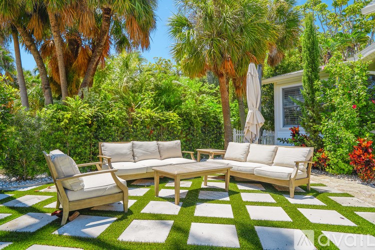 A white outdoor furniture set is placed on a green and white checkered rug.