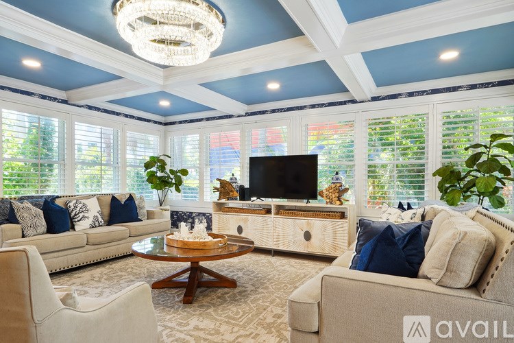 A living room with a white couch, a wooden coffee table, and a chandelier.