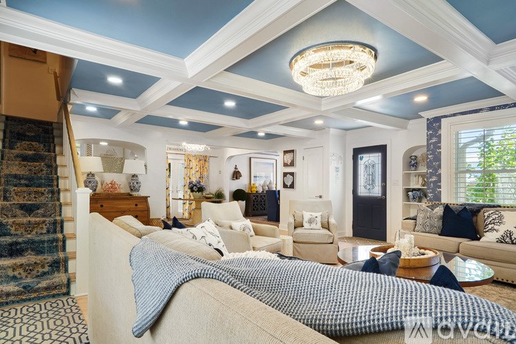 A living room with a beige couch and a chandelier.