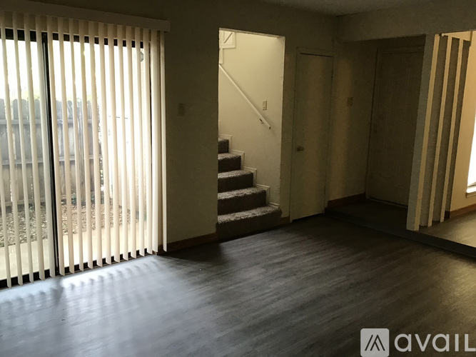 A room with wooden floors and a staircase leading to another room.