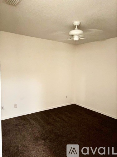 A room with a fan on the ceiling and a carpeted floor.