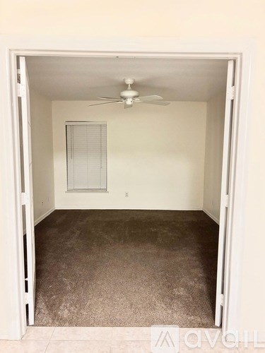 A room with a ceiling fan and carpeted floor.