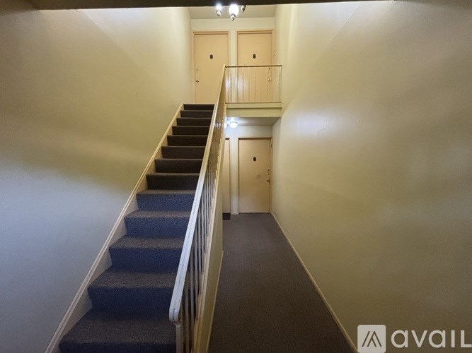 A staircase with a carpeted runner and wooden steps leading to a landing with two doors.