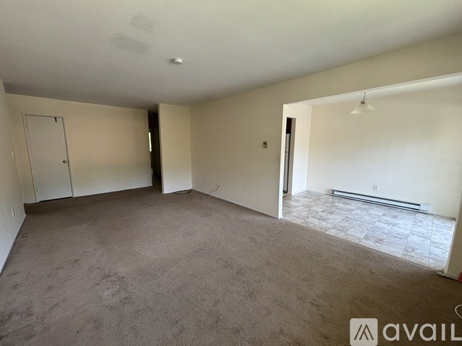 A spacious room with carpeted floor and white walls.
