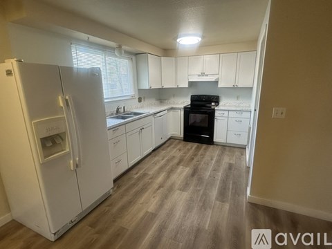 A kitchen with white appliances and wooden floors.