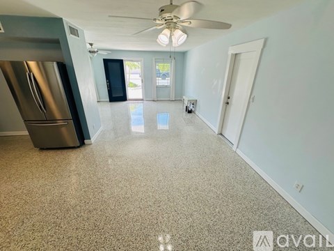 A spacious kitchen with a stainless steel refrigerator and a ceiling fan.