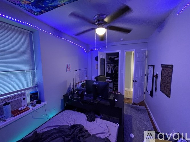 A bedroom with a bed, a ceiling fan, and a window with blinds.