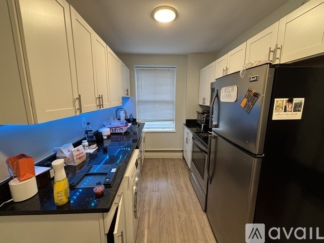A kitchen with a black fridge and a black counter top.