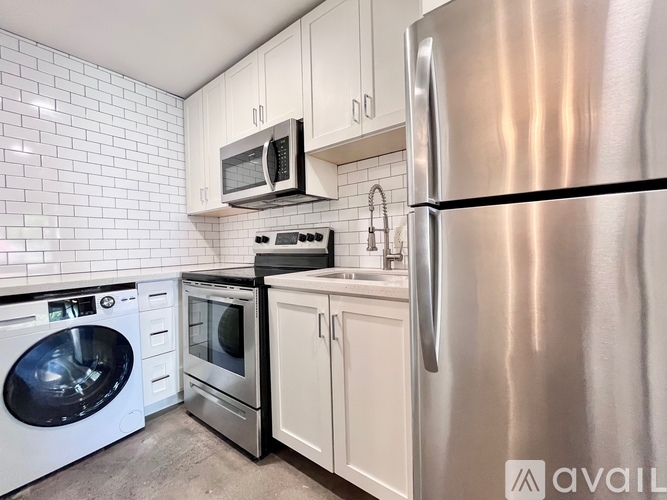 A kitchen with a stainless steel refrigerator, microwave, oven, dishwasher, and washing machine.