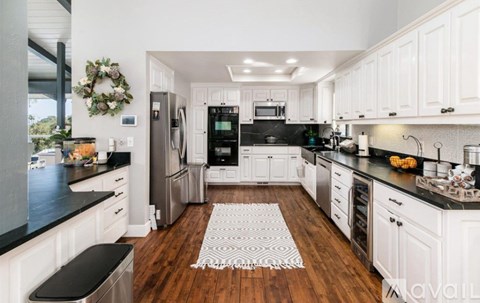 A kitchen with white cabinets and a black countertop.