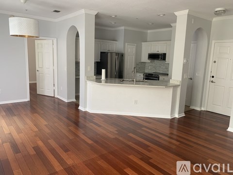 A spacious kitchen with wood flooring and white walls.