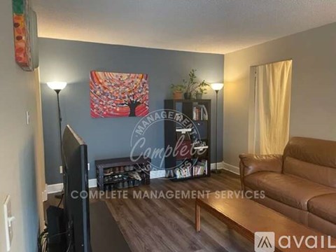 A living room with a brown couch and a sign that says "Complete Management Services".