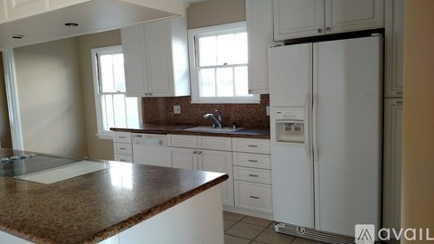 A kitchen with white cabinets and a granite countertop.