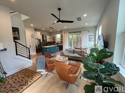 A living room with a brown chair and a ceiling fan.