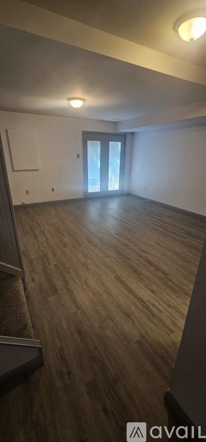 A room with wooden flooring and a door leading to a balcony.