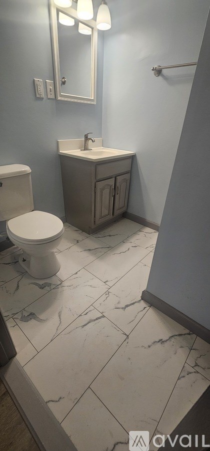 A bathroom with a toilet, sink, and mirror.