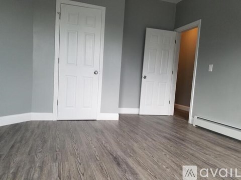 A room with two white doors and wooden flooring.