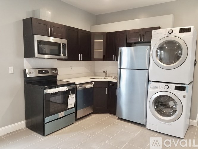 A kitchen with a black oven and microwave, a white refrigerator, and a white washing machine.
