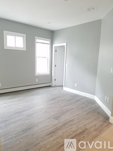 A room with wooden flooring and a door leading to another room.