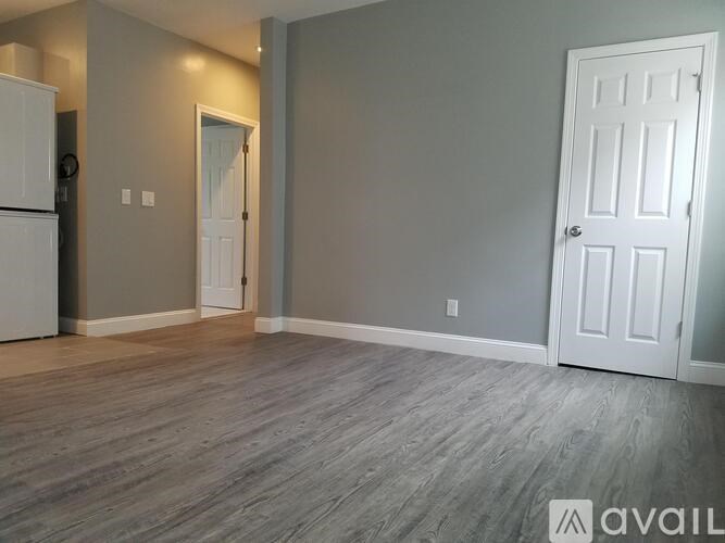 A room with a white door and a wooden floor.