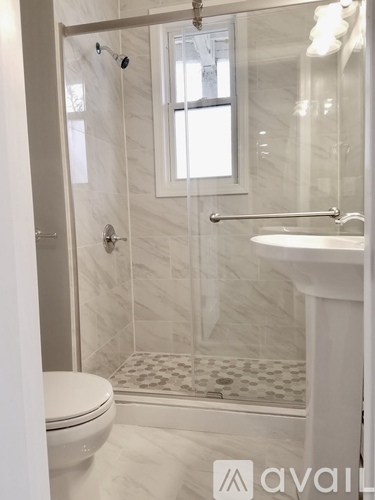 A white bathroom with a toilet, sink, and shower.