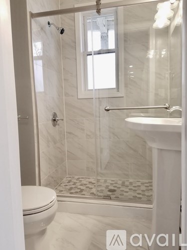 A white bathroom with a toilet, sink, and shower.