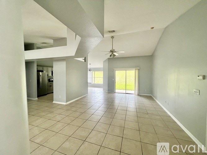 A spacious living room with a ceiling fan and sliding glass doors leading to a patio.