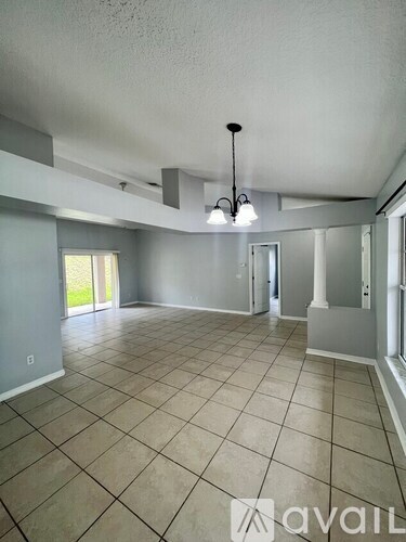 A spacious room with tile flooring and a chandelier hanging from the ceiling.