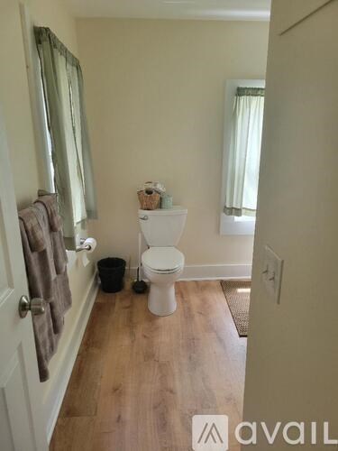 A bathroom with a toilet, a mirror, and a trash can.