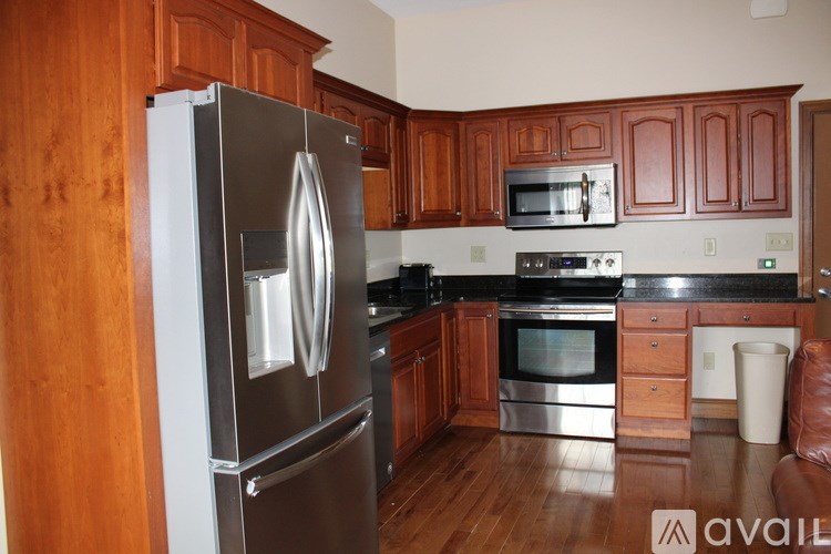 A kitchen with wooden cabinets and a stainless steel refrigerator.