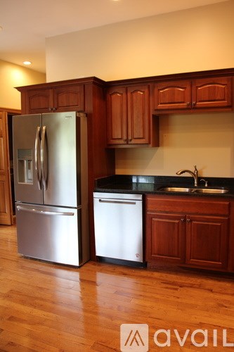 A kitchen with wooden cabinets and a stainless steel refrigerator.