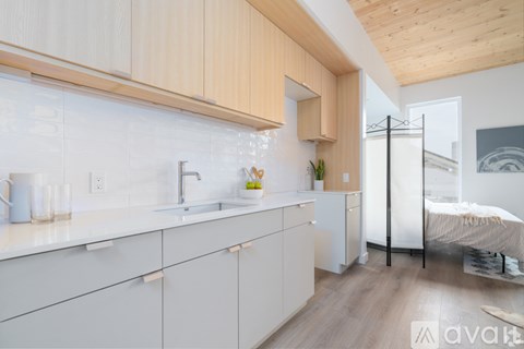 A modern kitchen with white cabinets and a wooden ceiling.