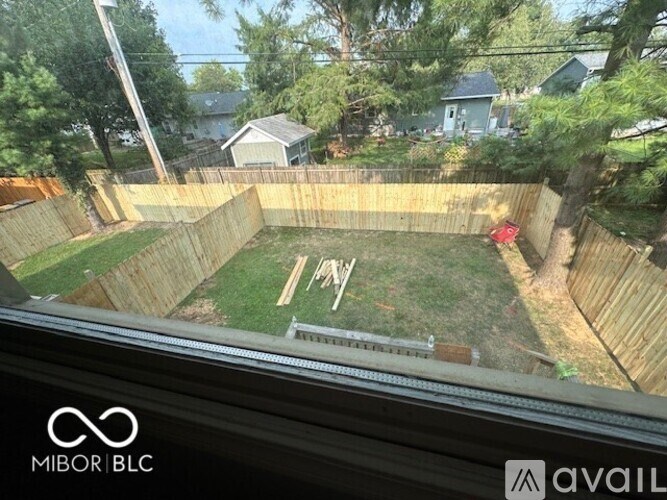 A backyard with a wooden fence and a green lawn.